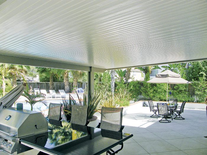 A patio with tables and chairs, covered in white awnings.