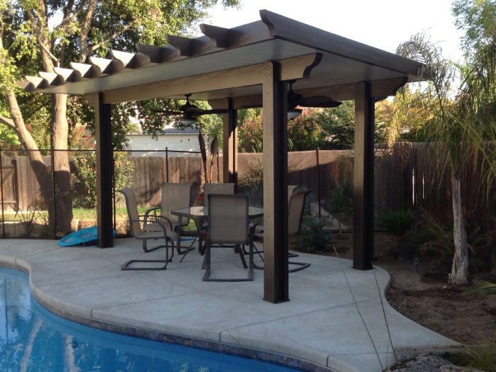 A pool with chairs and tables under an awning.