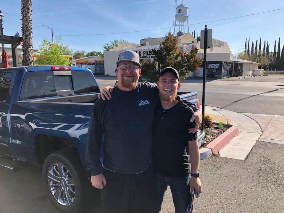 Two men wearing hats standing behind a truck